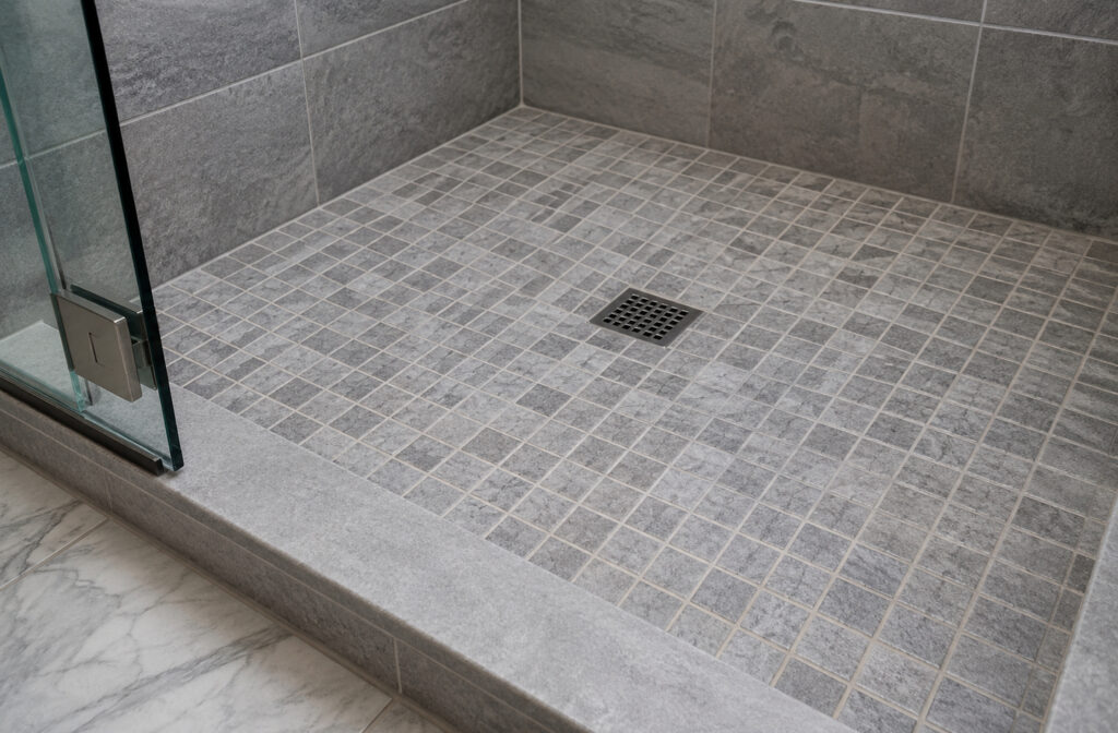 Non-slip bathroom flooring: 1-inch slip-resistant mosaic tiles surround a central drain with a low-profile threshold transition for aging in place
